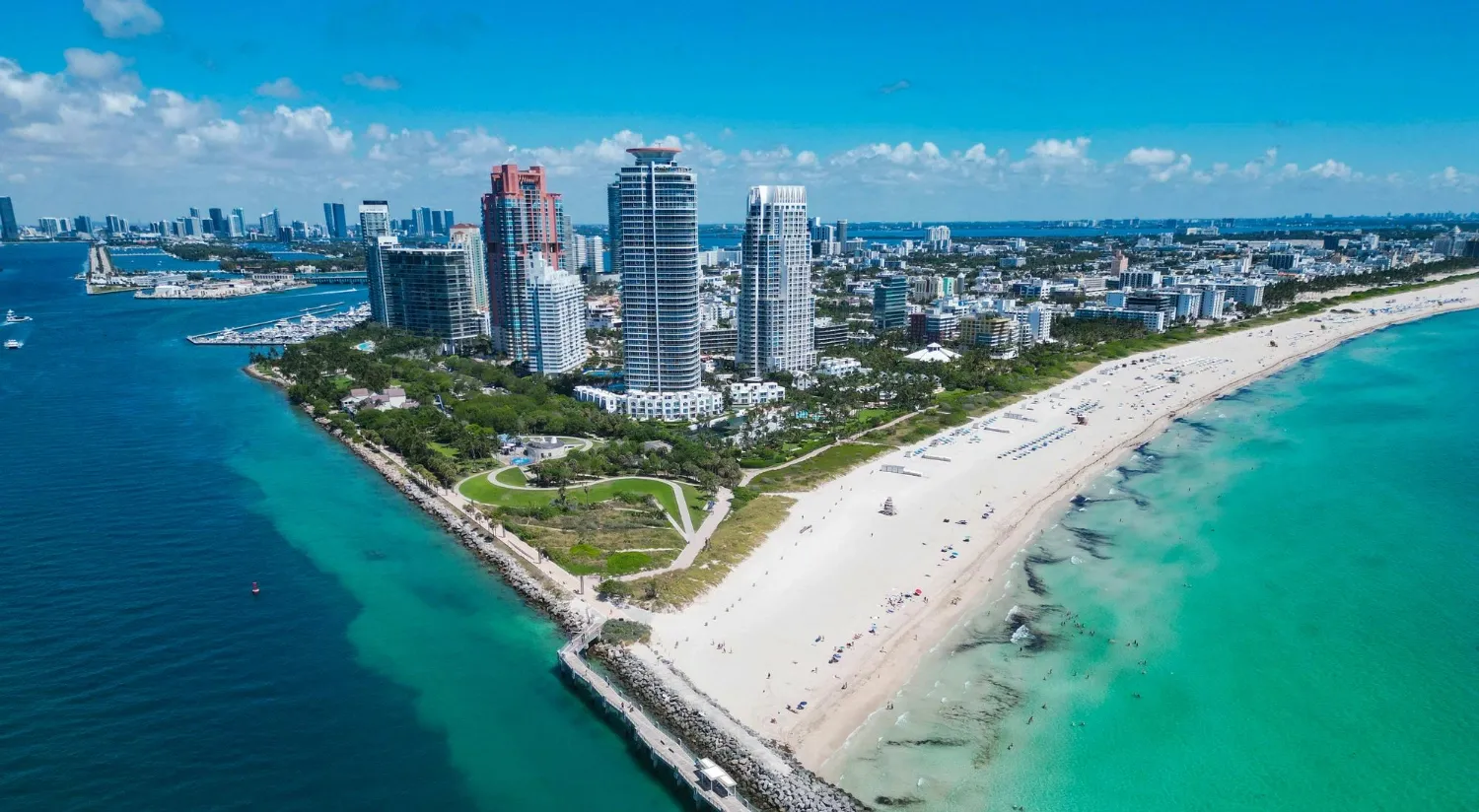 Aerial view of Miami Beach coastline with turquoise water and city skyline.