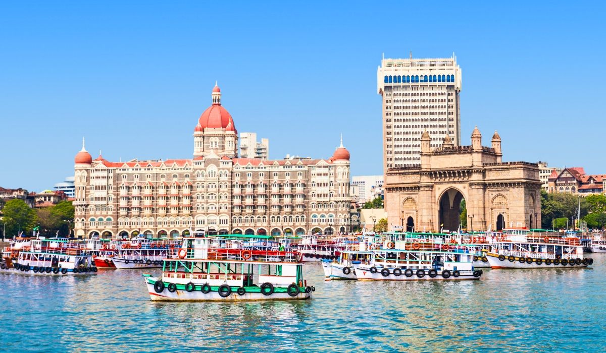 View of the Gateway of India and the iconic Taj Mahal Palace Hotel with boats docked in the water in Mumbai.