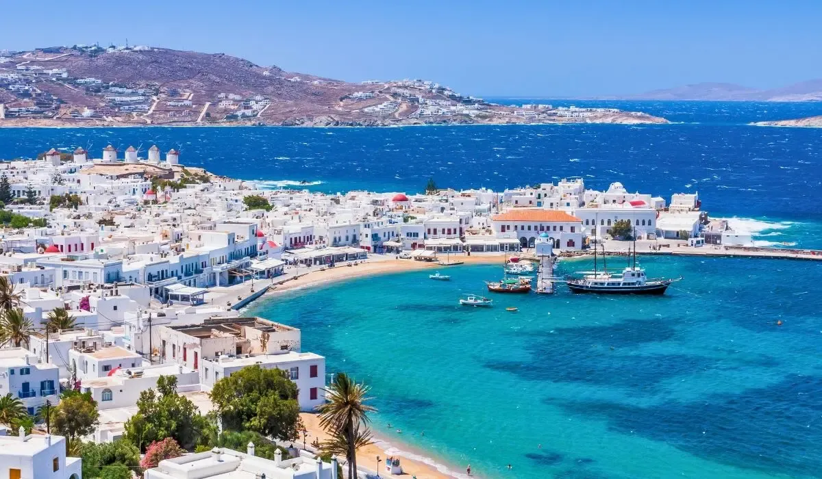 Panoramic view of Mykonos with whitewashed buildings and azure bay, enticing Canadians to invest in Greek property and benefit from secure CAD to EUR money transfers for real estate deals.