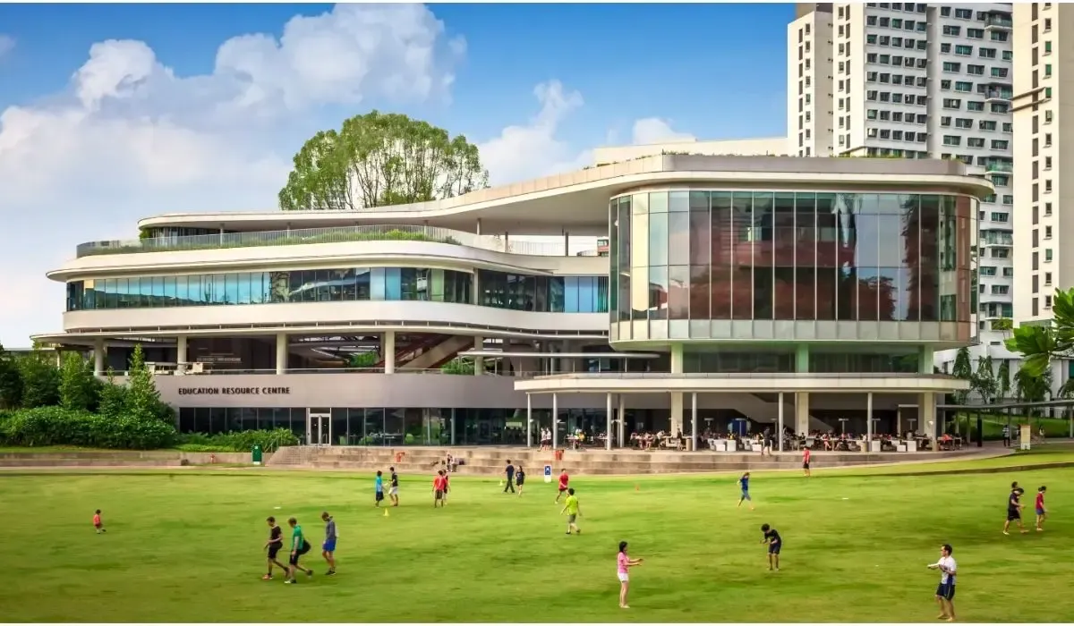 A panoramic view of the National University of Singapore campus, featuring modern academic buildings surrounded by lush greenery under a clear sky.