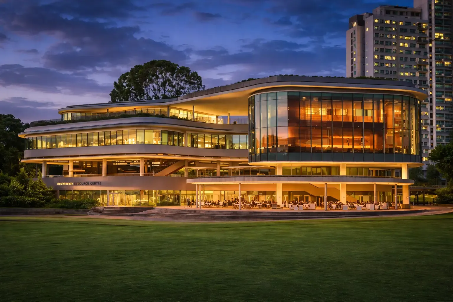 A panoramic view of the National University of Singapore campus, featuring modern academic buildings surrounded by lush greenery under a clear sky.