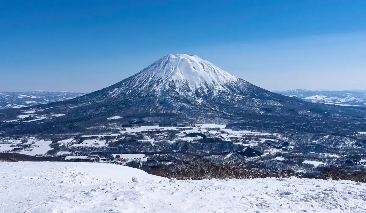 Majestic winter landscape of Mount Yotei in Hokkaido, Japan, surrounded by snow-covered valleys under clear blue skies. Canadians interested in ski properties or second homes in Japan can benefit from competitive CAD to JPY rates and seamless large-money transfers with MTFX.
