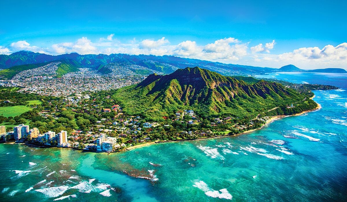 Aerial view of Diamond Head crater and Waikīkī coastline in Honolulu, Oʻahu, Hawaii, surrounded by turquoise waters and urban neighborhoods.