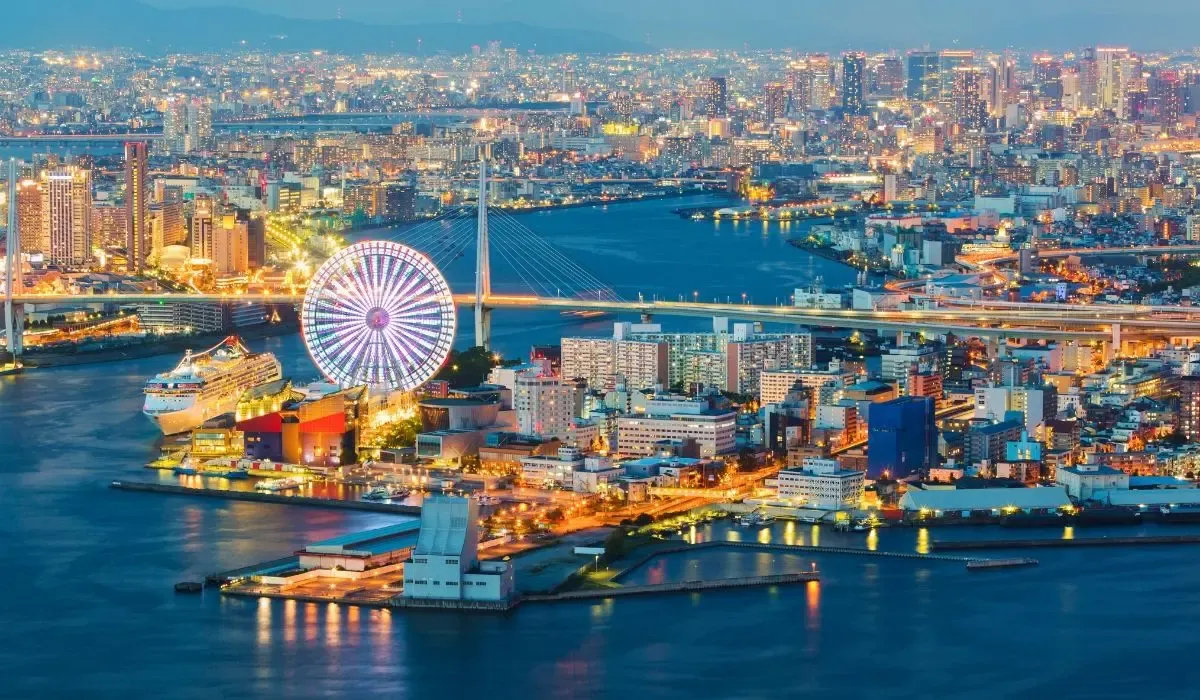 Night view of Osaka Bay featuring the illuminated Tempozan Ferris Wheel, vibrant harborfront, and high-rise cityscape. Canadians buying property in Japan can secure favorable CAD to JPY exchange rates and lower transfer fees for real estate purchases with MTFX.