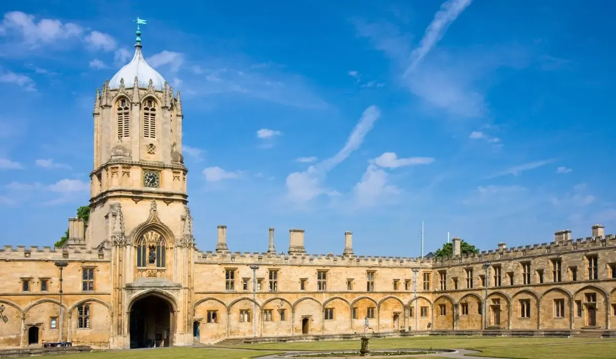 Historic courtyard and Tom Tower at Christ Church, University of Oxford, under a bright blue sky.