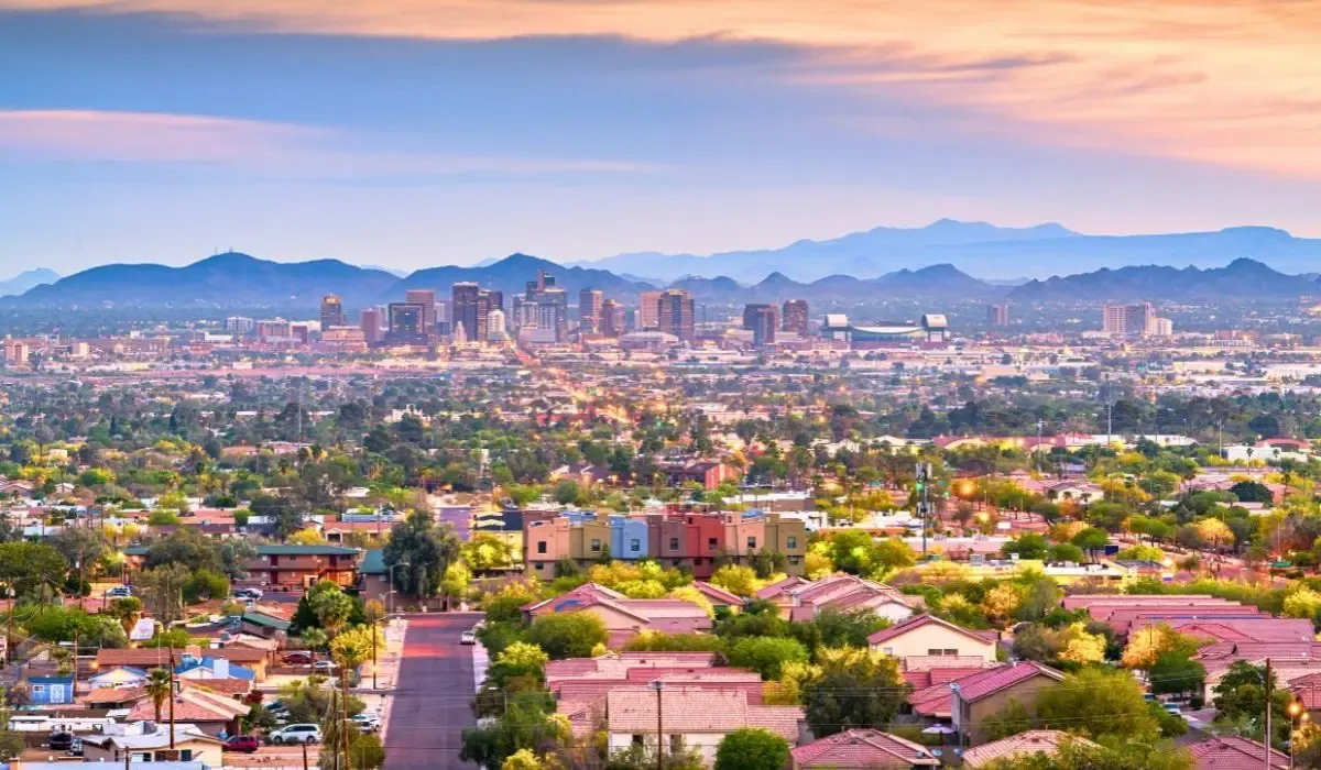 An aerial shot of Phoenix's skyline, featuring modern skyscrapers, sprawling suburbs, and desert landscapes extending to the horizon.