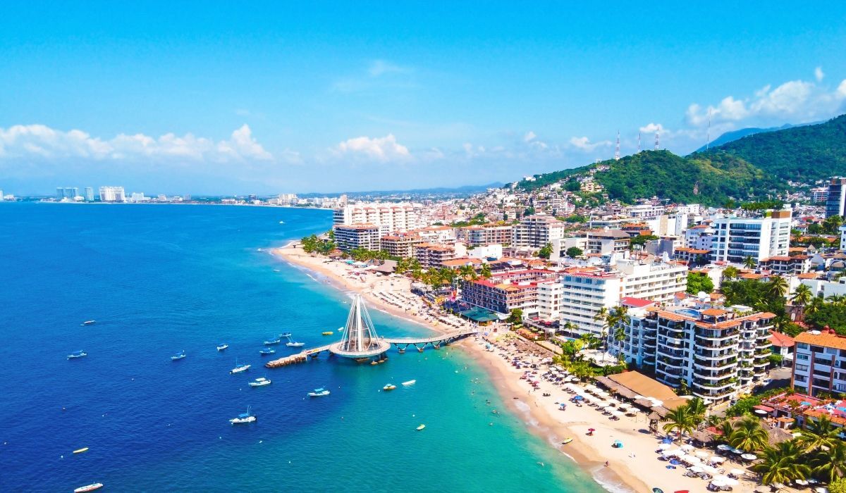 Aerial view of Puerto Vallarta’s coastline in Mexico, lined with beaches, hotels, and boats on turquoise waters.