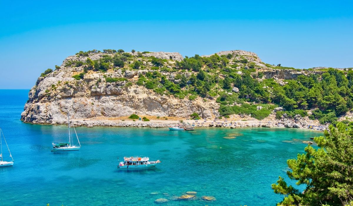 Turquoise waters and boats anchored at Anthony Quinn Bay in Rhodes, Greece.