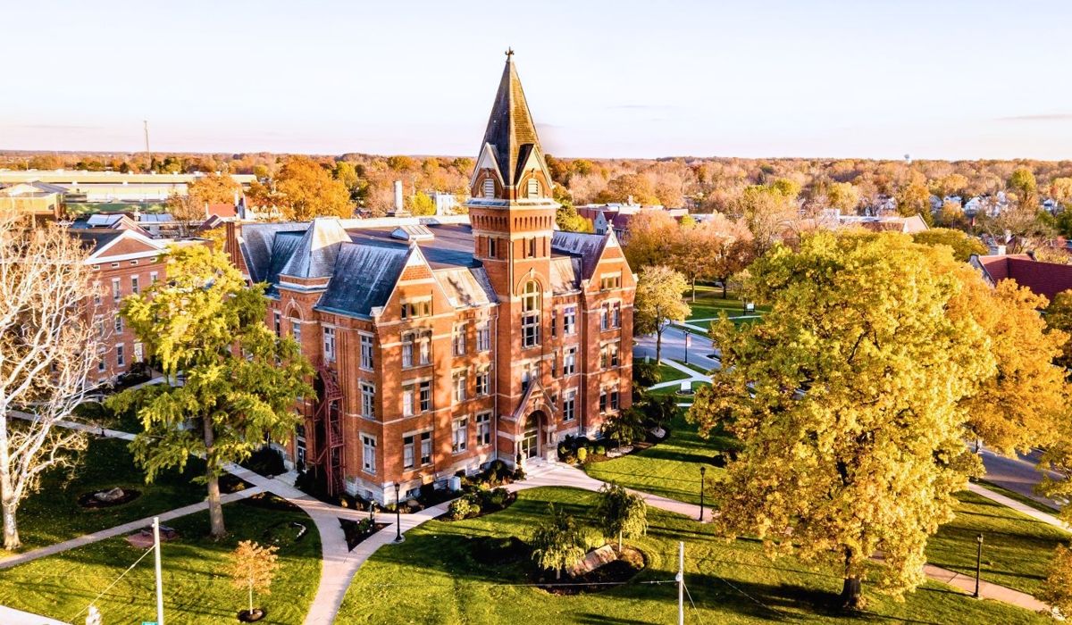 An aerial view of a red-brick academic building at Ruprecht Karls University Heidelberg, surrounded by autumn-colored trees on a traditional European-style campus.