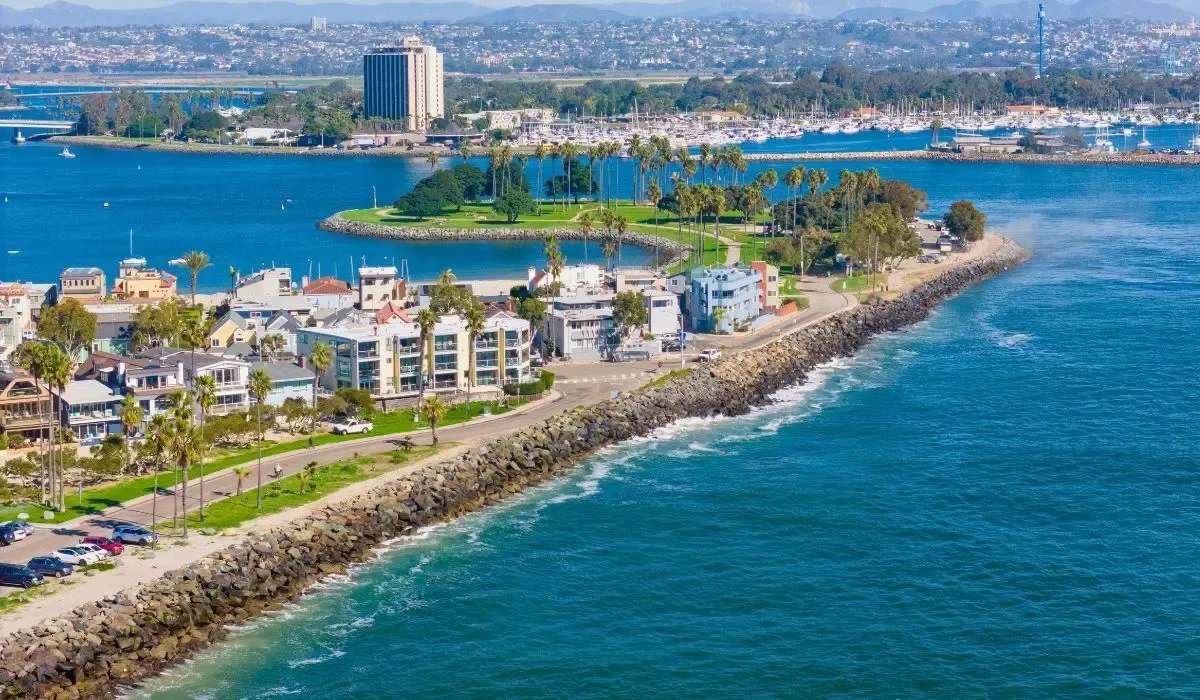 A vibrant image of San Diego's waterfront, featuring the downtown skyline, marina with docked boats, and clear blue skies.