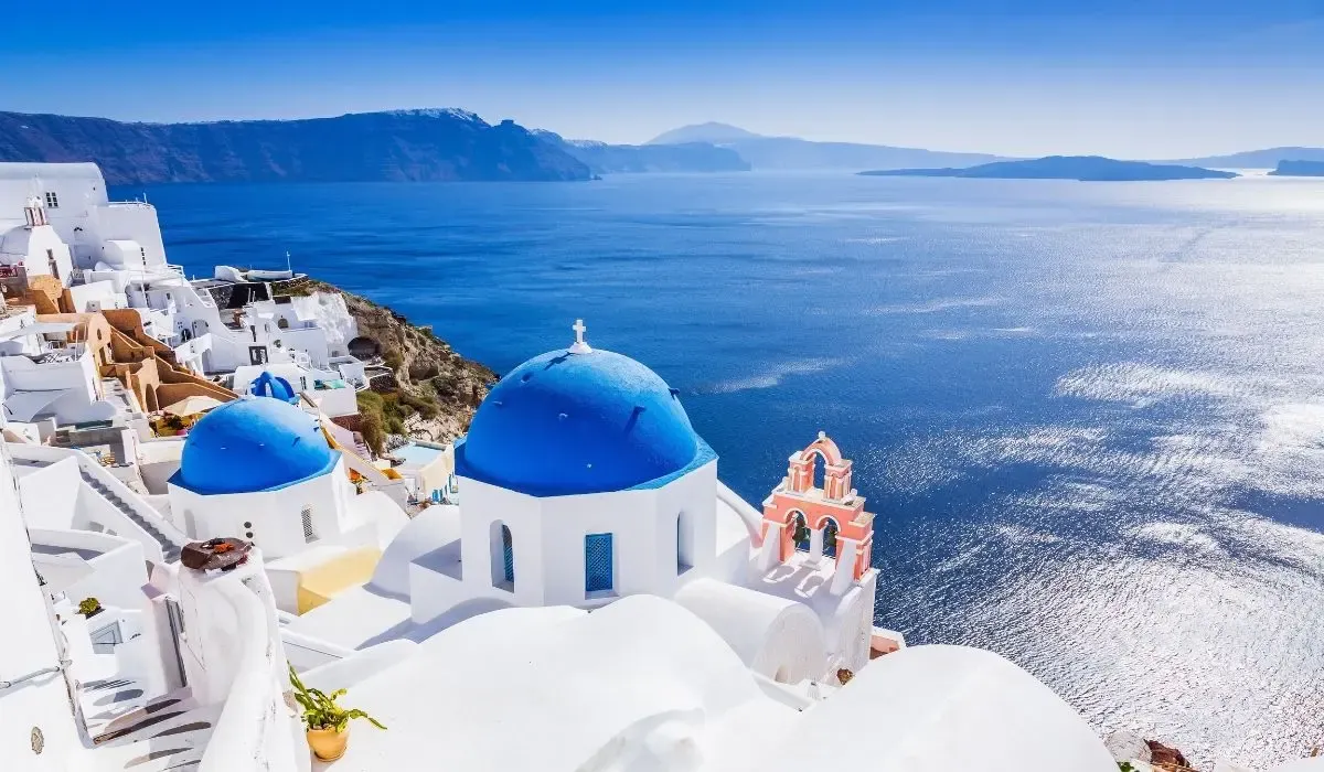 Iconic blue-domed churches overlooking the sparkling Aegean Sea in Santorini, Greece — ideal for Canadians buying property abroad and securing competitive CAD to EUR exchange rates for their investment.
