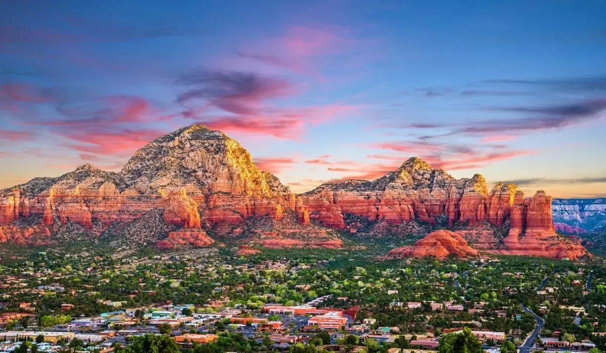A picturesque scene of Sedona's red rock formations, with towering buttes, green vegetation, and a clear sky enhancing the natural beauty.