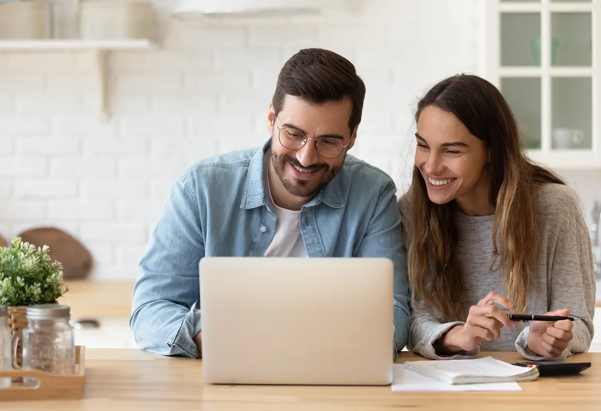 Individuals comparing CAD to USD exchange rates on a laptop at home while planning an international money transfer.