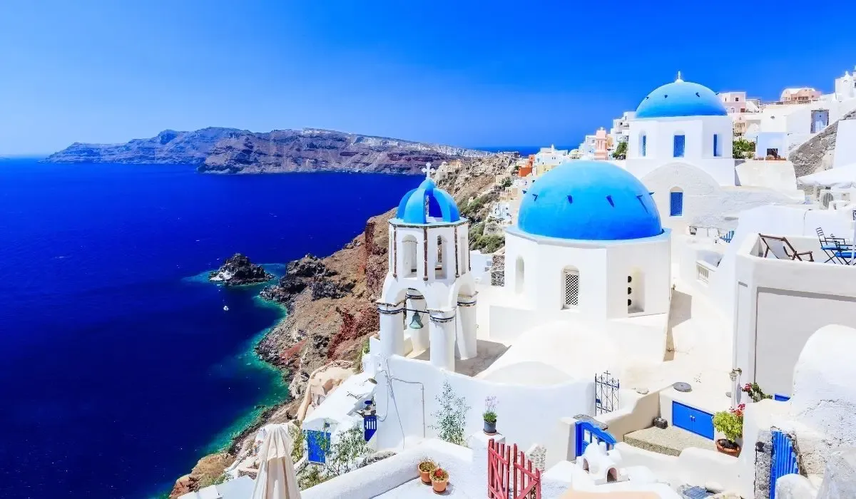 Whitewashed buildings with blue domes overlooking the deep blue Aegean Sea in Santorini, Greece — a prime spot for Canadians buying property in Greece. Convert CAD to EUR at low fees for Greek real estate deals with MTFX.