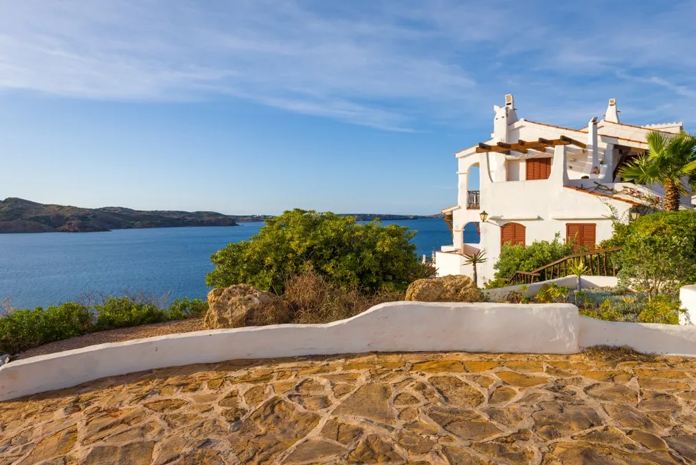 Mediterranean-style seaside villa in Spain overlooking a scenic bay with coastal landscapes and clear blue skies.