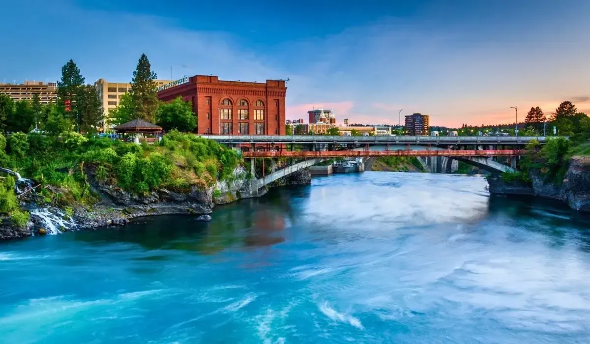 A panoramic view of Spokane's downtown area with the Spokane River flowing through Riverfront Park, surrounded by historic buildings and lush greenery.