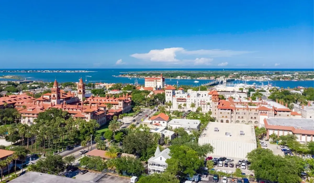 A historic scene of St. Augustine showcasing the Castillo de San Marcos fortress, cobblestone streets, and colonial-style buildings.