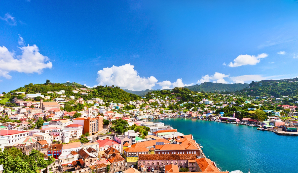Scenic view of St. George’s, Grenada, showing colorful buildings on hillsides around a calm harbor under a clear sky.