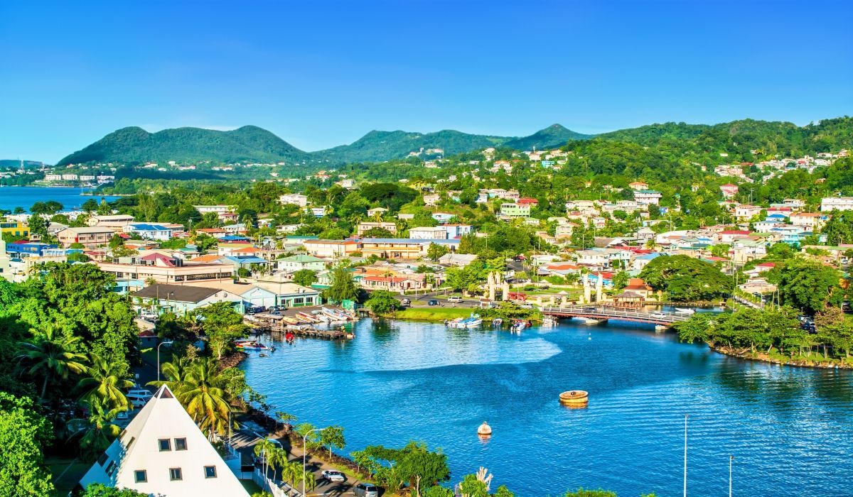 Waterfront view of Castries, St. Lucia with colorful buildings, a harbor, and green forested hills.