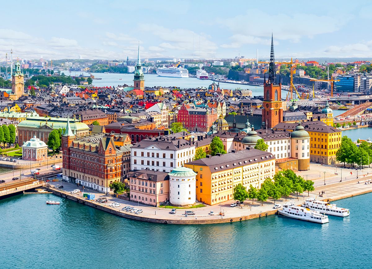 Vibrant cityscape of Stockholm, Sweden, featuring historic architecture, waterfront views, and colorful buildings under a clear blue sky.
