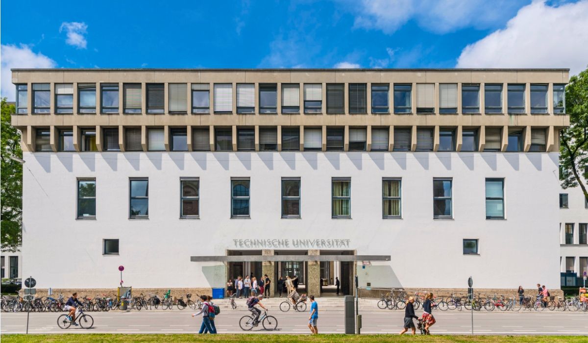 Main entrance of the Technical University of Munich in Germany, with students cycling and walking along the campus front.