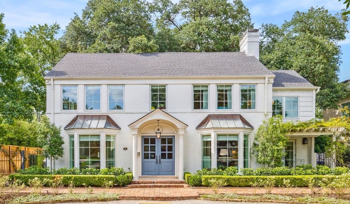 Classic white house in Texas with front porch and expansive green lawn.