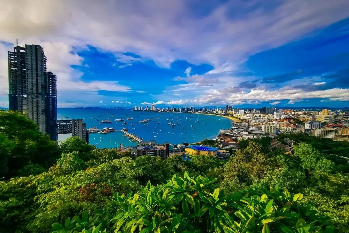 Panoramic view of Pattaya, Thailand, with coastline, city buildings and blue sky.