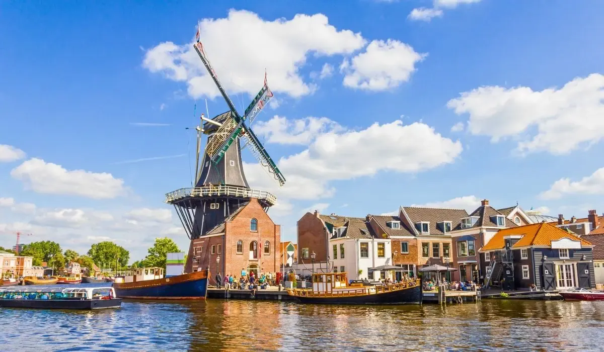 A picturesque canal scene in Amsterdam, Netherlands, with traditional Dutch houses lining the waterway and bicycles parked along the bridge.