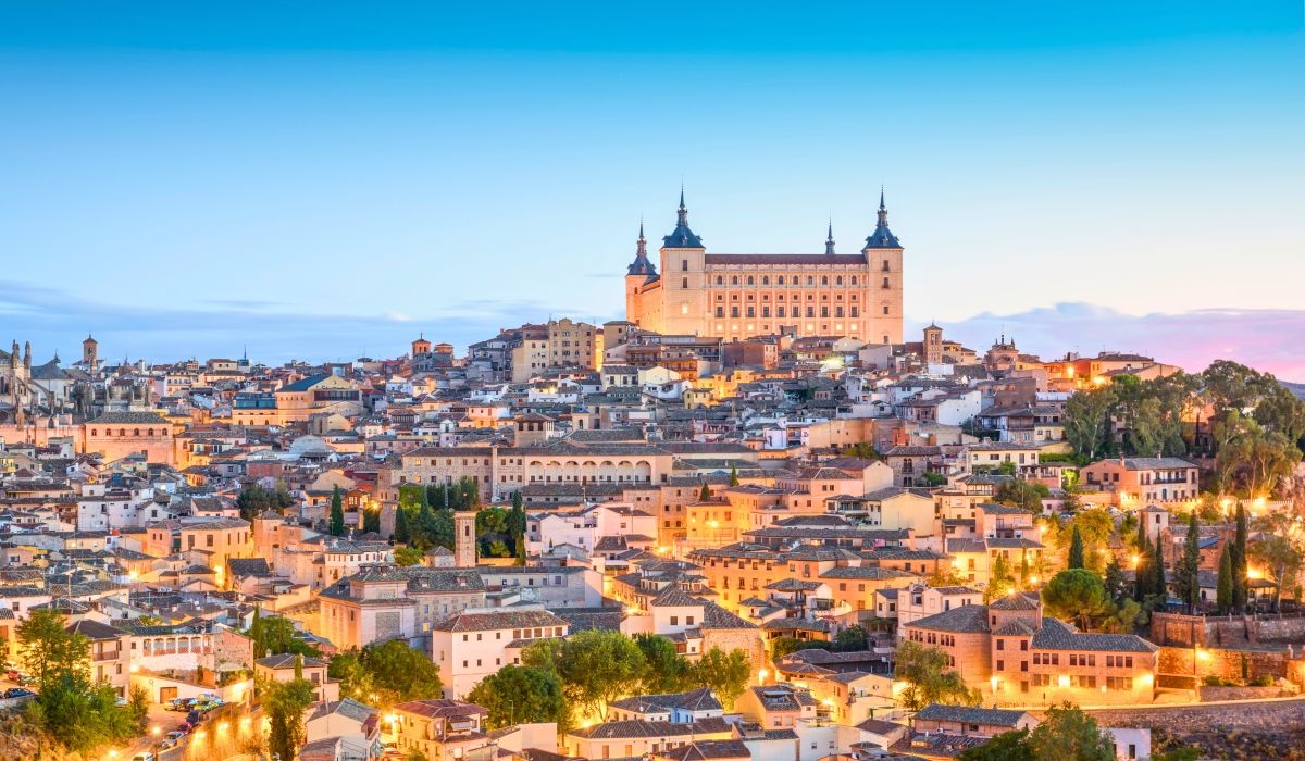 A twilight view of Toledo’s illuminated cityscape, highlighting the Alcázar fortress and historic architecture.
