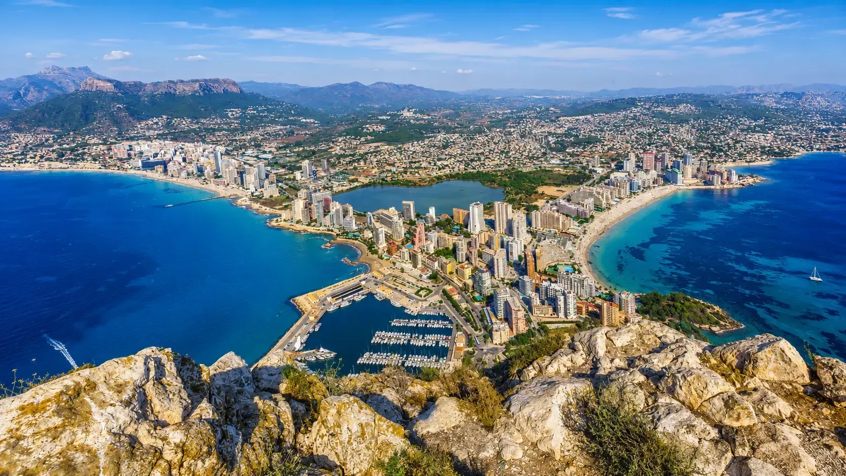 Mediterranean coastal city with beaches, marina, and mountain views.