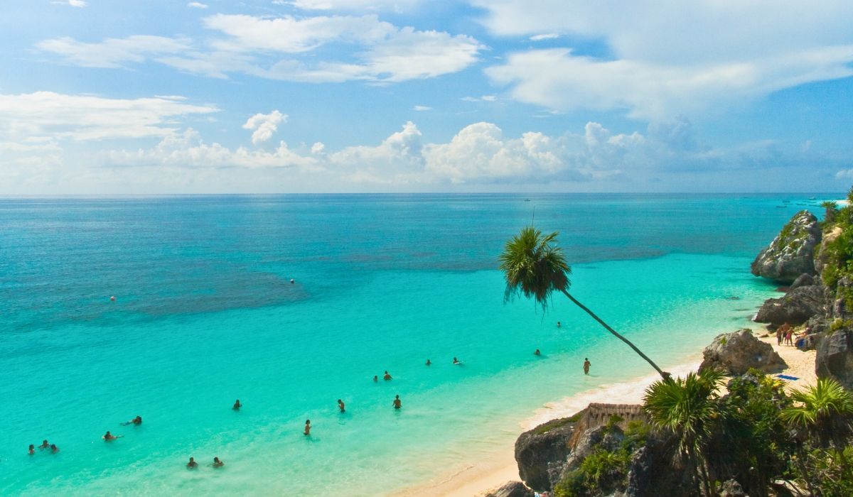 A picturesque image of Tulum's beachfront, displaying ancient Mayan ruins atop cliffs overlooking the Caribbean Sea.
