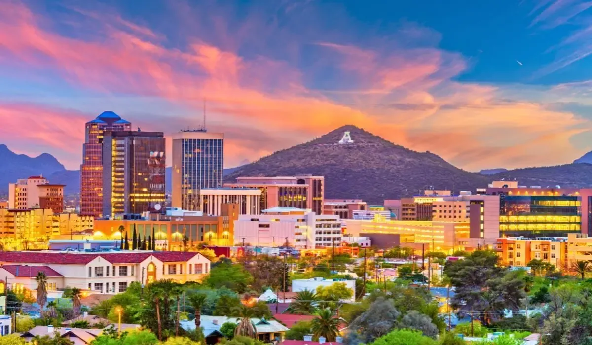 A vibrant view of downtown Tucson, showcasing historic adobe buildings, palm trees, and the backdrop of the Santa Catalina Mountains.