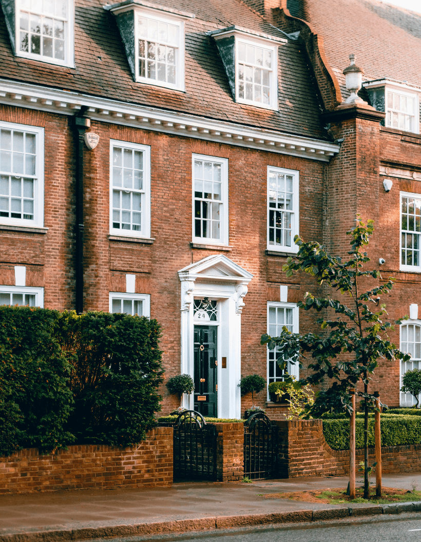 Classic British red-brick townhouse with white-framed windows and a black door, representing real estate investment opportunities in the UK.