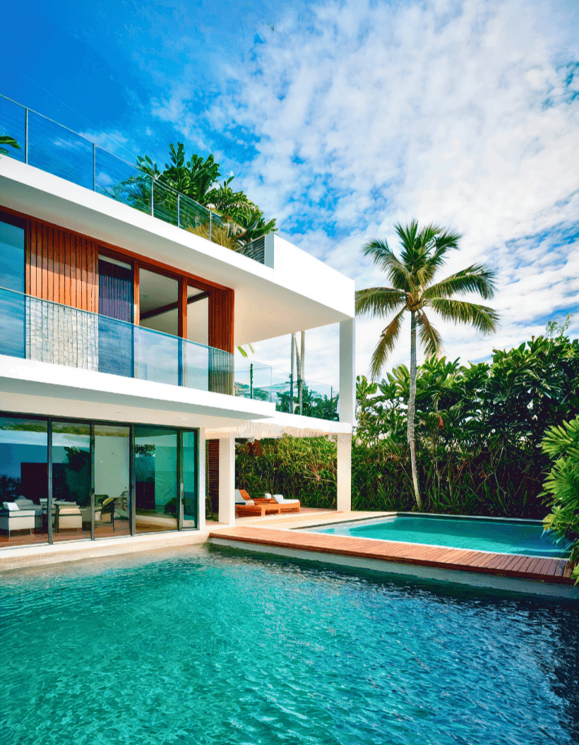 Modern luxury home in the USA with poolside view, palm trees, and blue sky.