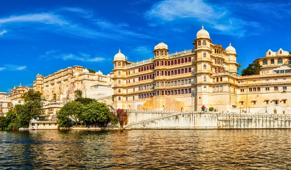 City Palace in Udaipur, India, reflecting on the lake under a clear blue sky.