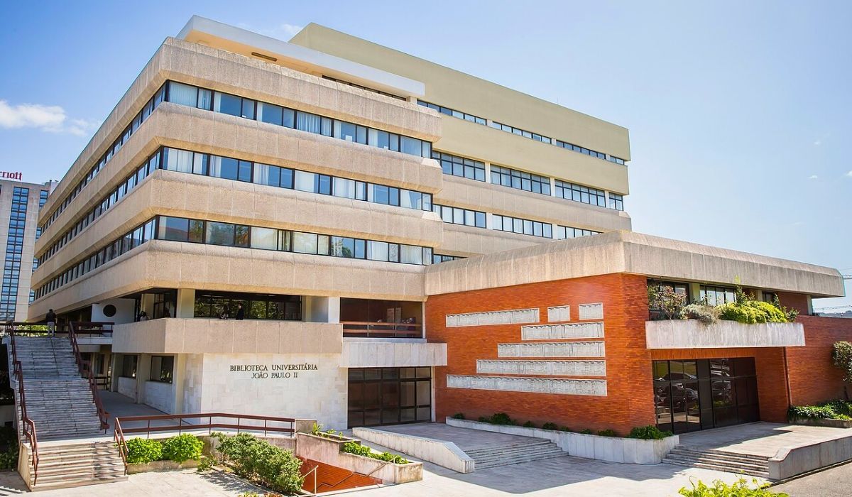A view of Universidade Católica Portuguesa's main campus, featuring modern architecture with clean lines and a welcoming entrance surrounded by greenery.