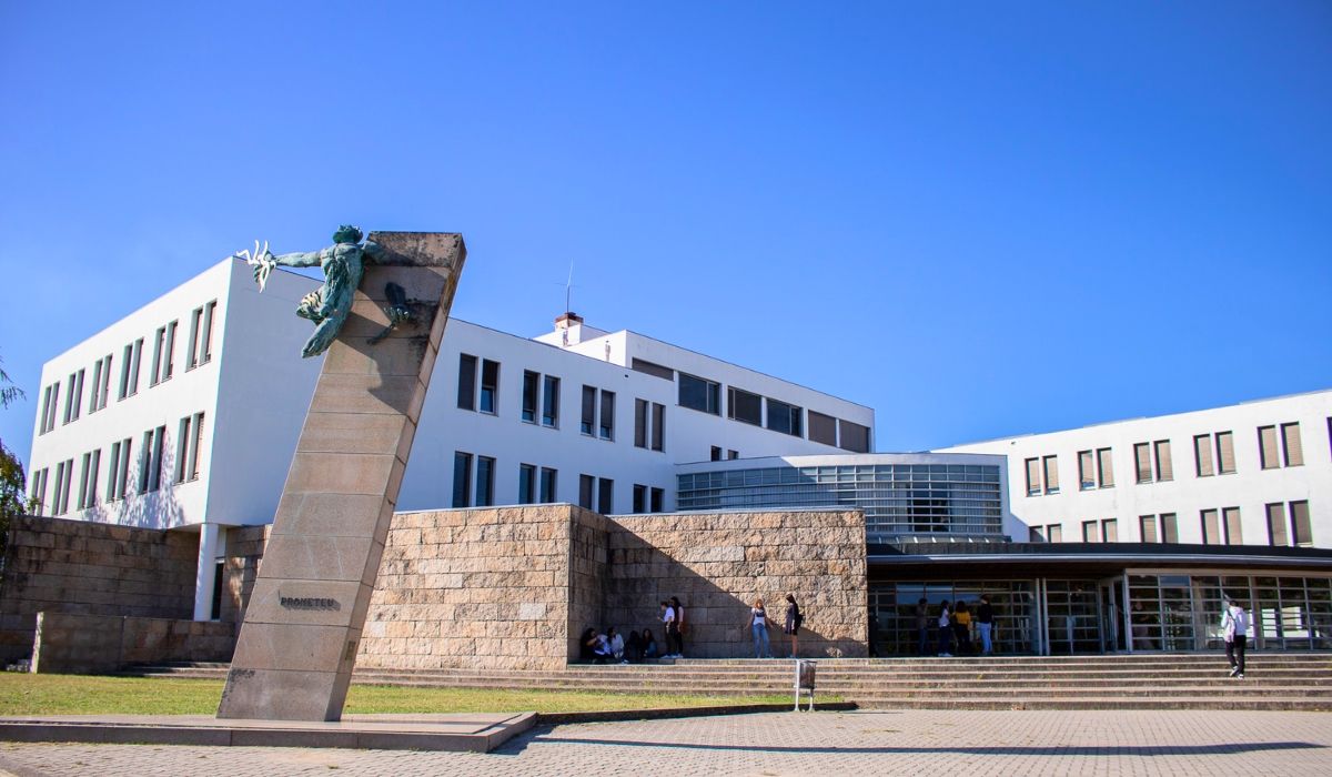 An image of Universidade do Minho's campus, showcasing contemporary buildings set against a backdrop of rolling hills and open spaces.
