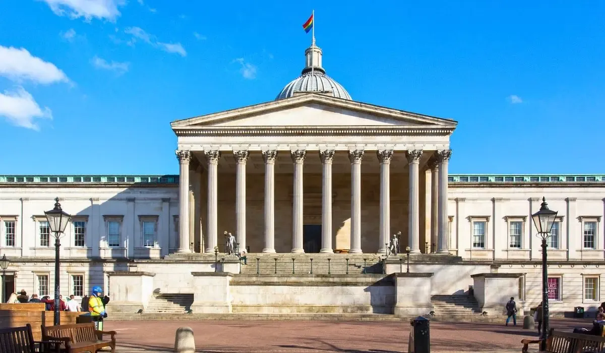 Neoclassical facade of University College London’s main building with large columns and a domed roof flying the pride flag.