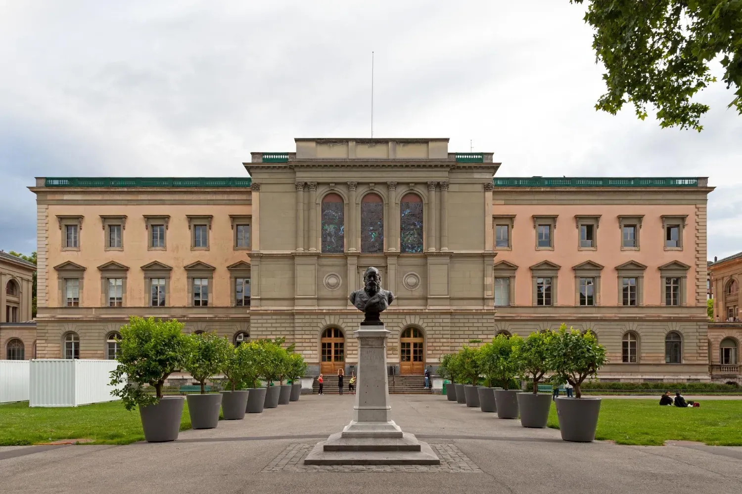 University of Geneva building in Switzerland with neoclassical architecture, landscaped grounds, and a central statue.