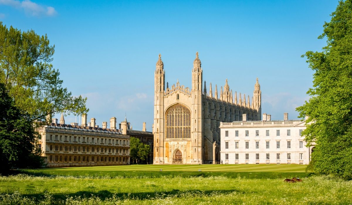 View of King’s College Chapel and the expansive green meadows of the University of Cambridge, United Kingdom, on a sunny day.