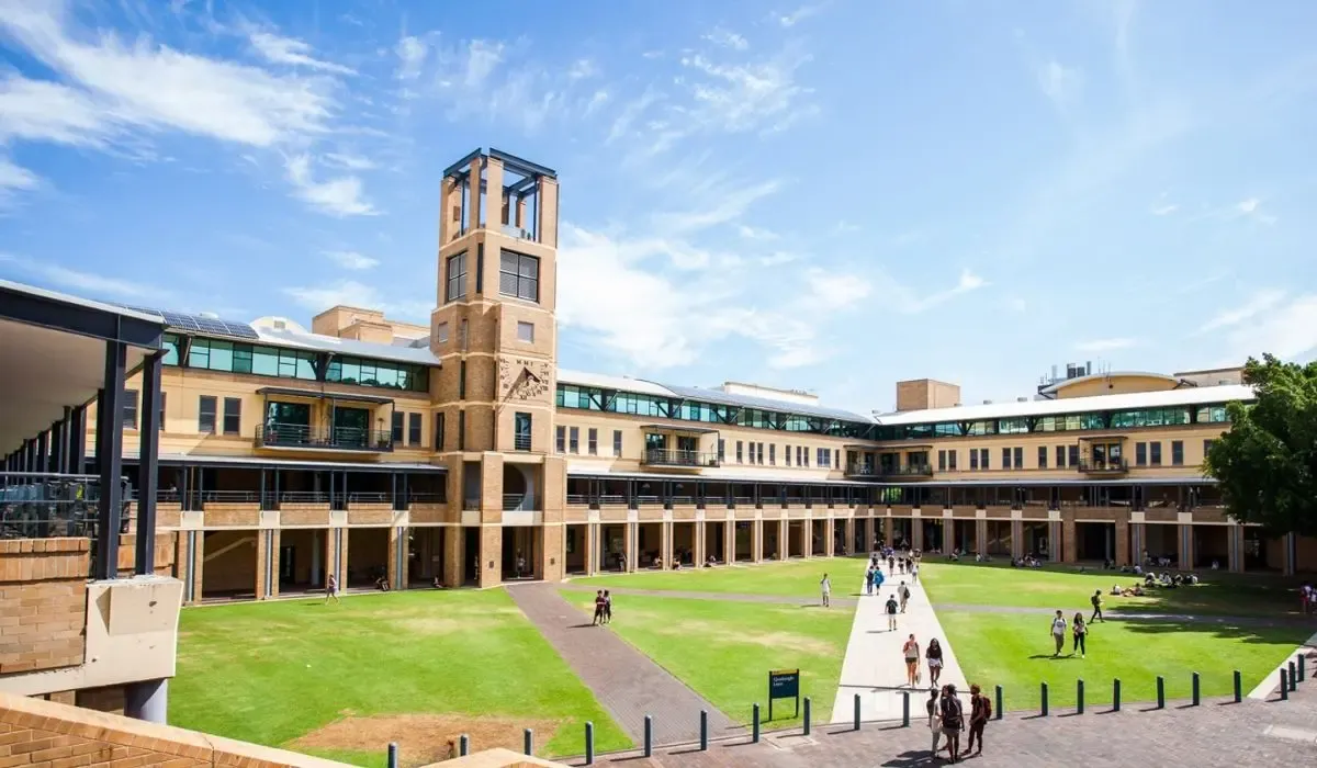 A bustling scene at the University of New South Wales, depicting students walking through the main quadrangle flanked by modern faculty buildings.