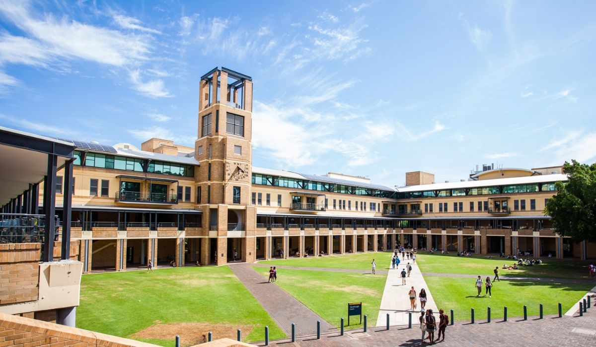 A bustling scene at the University of New South Wales, depicting students walking through the main quadrangle flanked by modern faculty buildings.