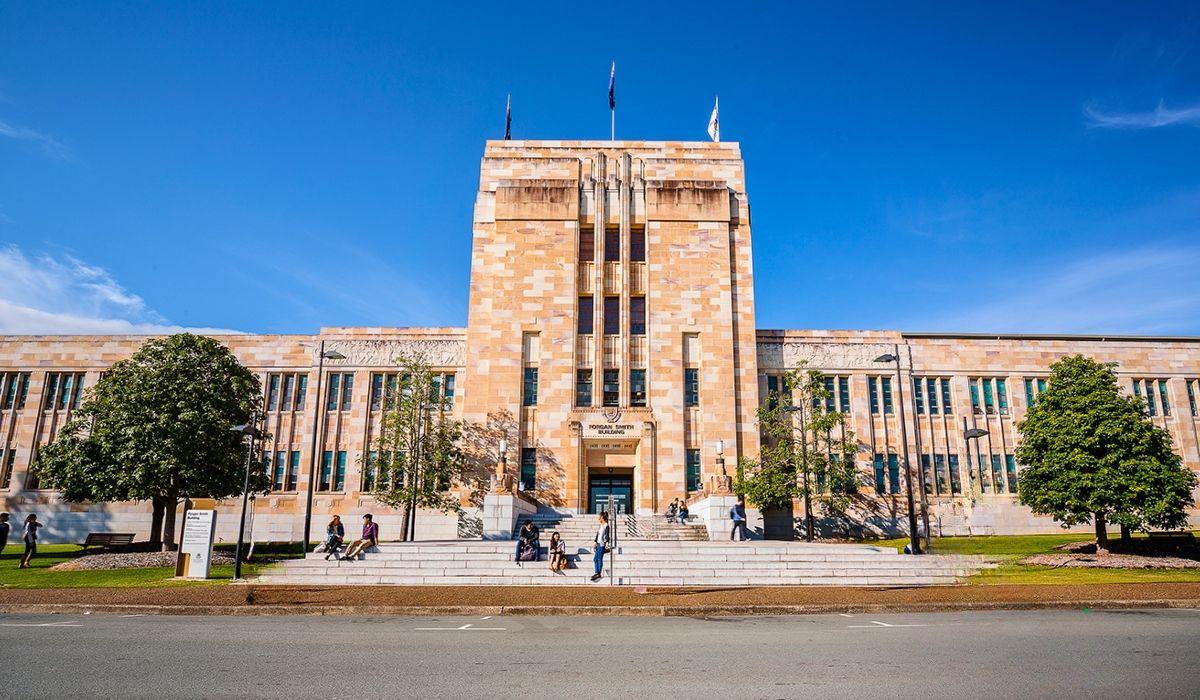 A vibrant view of the University of Queensland's Great Court, showcasing heritage-listed sandstone buildings and well-manicured lawns.