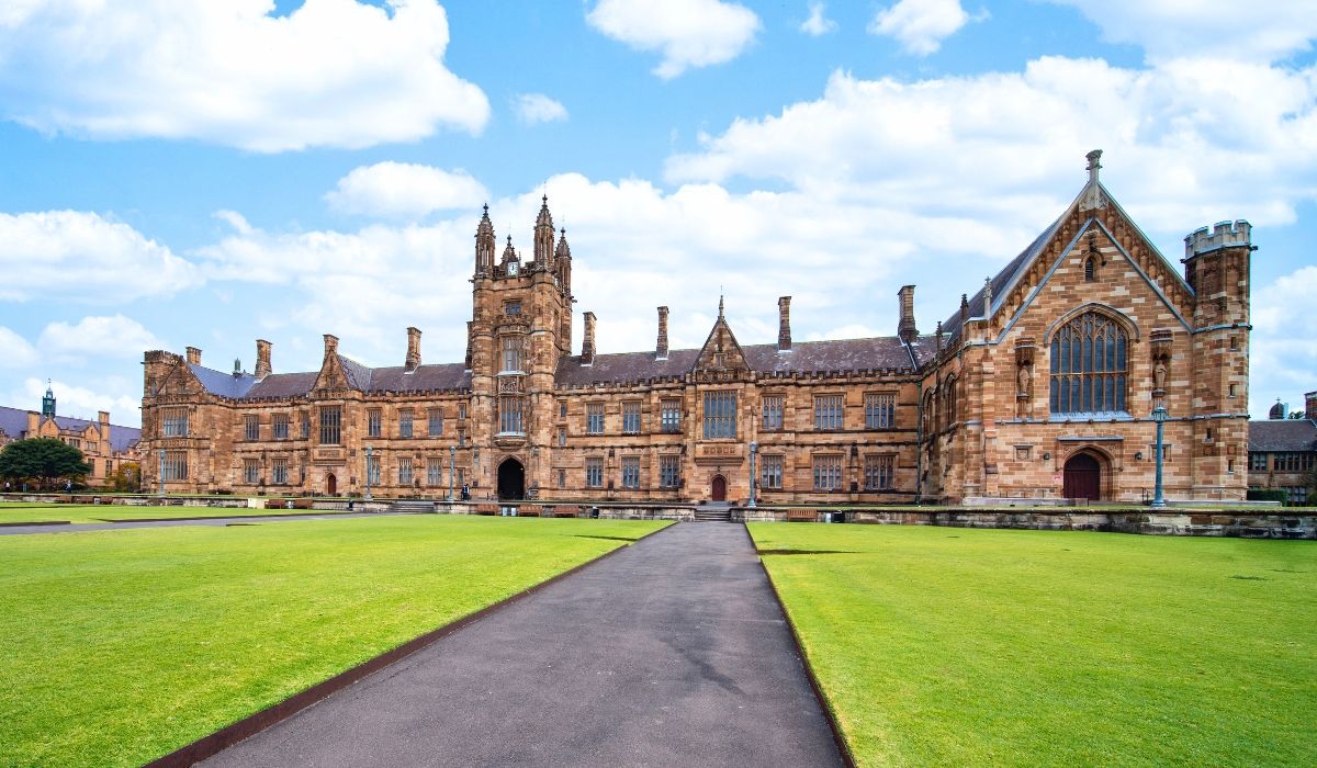 Front view of the University of Sydney’s iconic sandstone quadrangle with Gothic architecture and manicured green lawns.