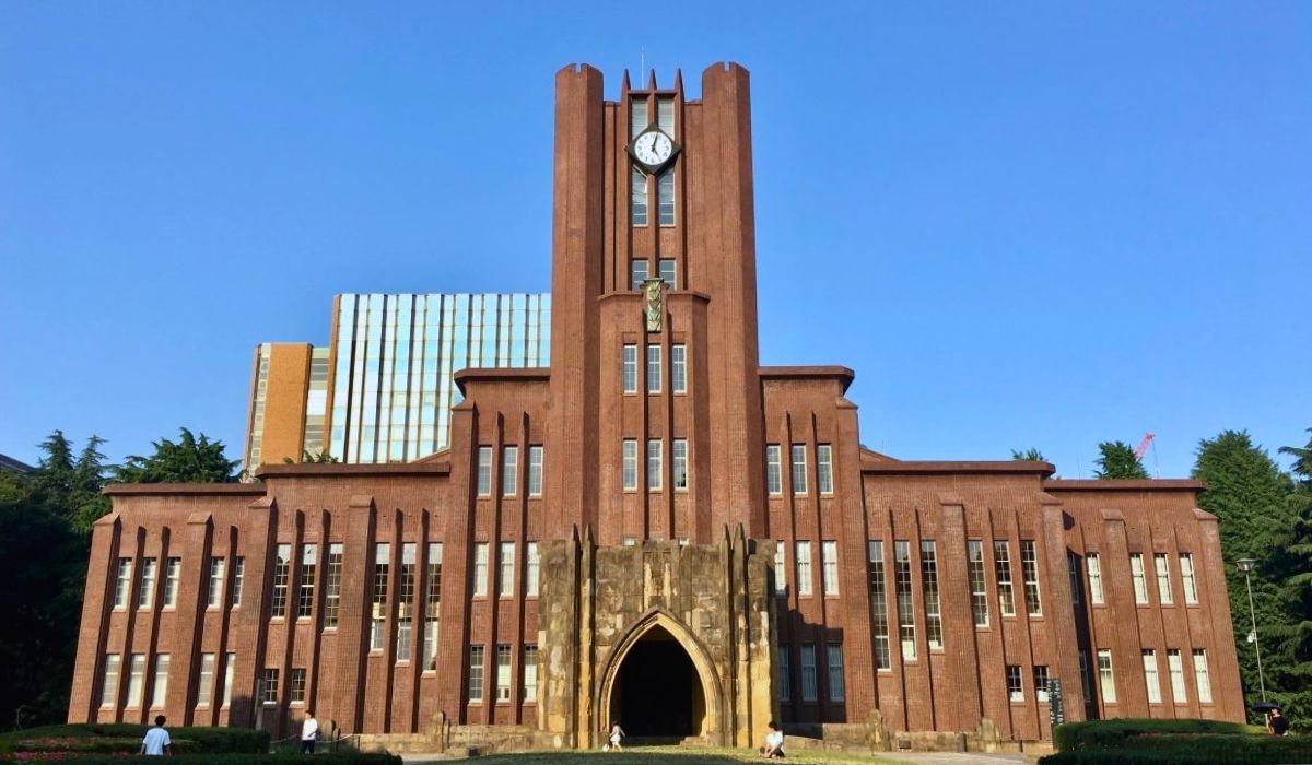 A panoramic view of the University of Tokyo's Yasuda Auditorium, showcasing its iconic red-brick façade and surrounding campus greenery.