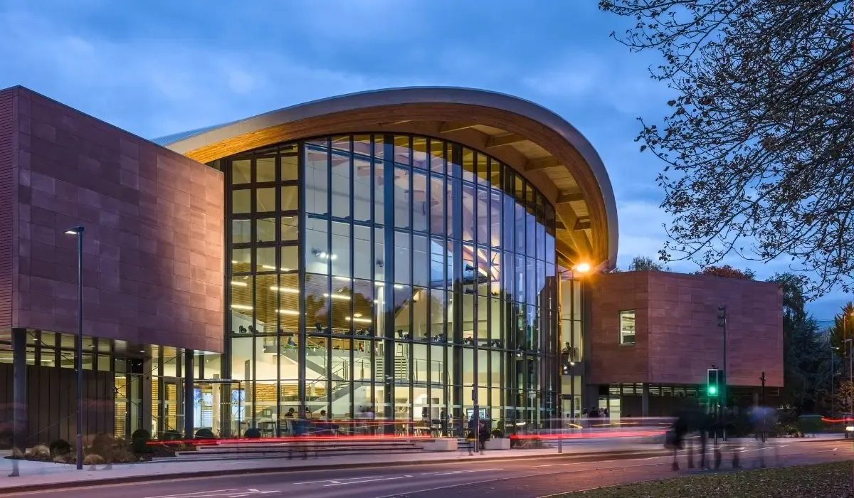 Modern glass and sandstone design of the Warwick Business School building at the University of Warwick during twilight.