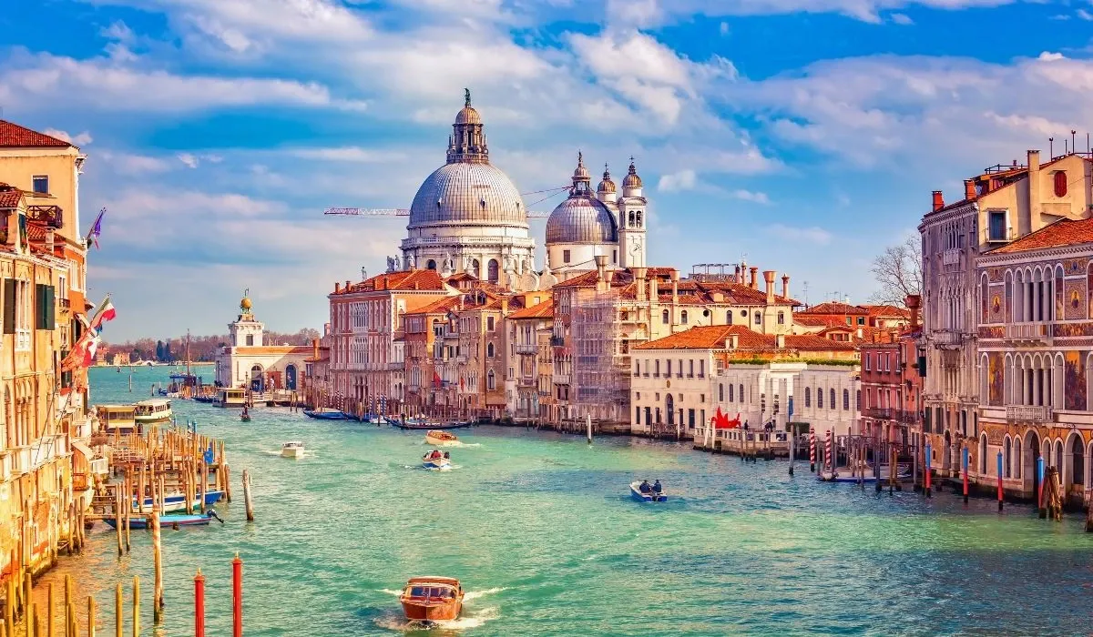 Scenic view of Venice’s Grand Canal lined with elegant historic buildings and the magnificent domes of Santa Maria della Salute under a vibrant sky. Canadians looking to purchase property in Italy can leverage competitive exchange rates and international transfers via MTFX.