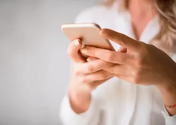 Close-up of a woman using a smartphone to send money overseas, emphasizing ease and convenience of digital transfers.