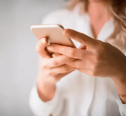 Close-up of a woman using a smartphone in a light-colored blouse