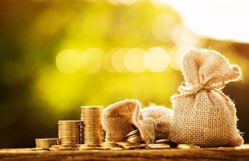 Burlap money bags and coins representing international money transfers and foreign bank account deposits.